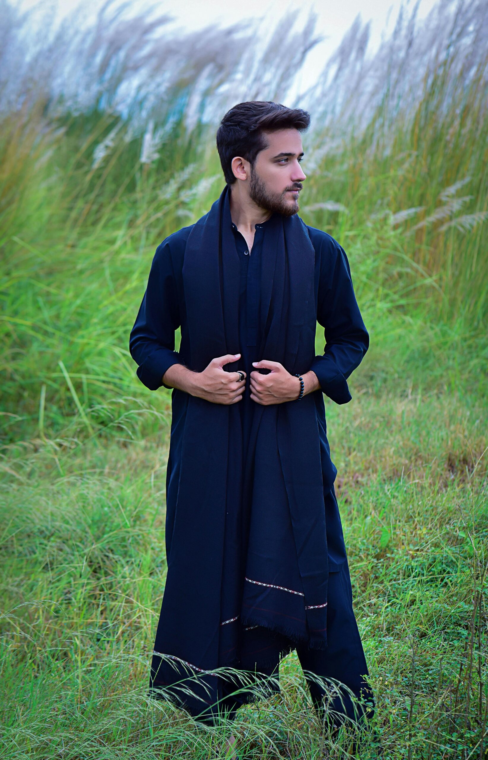 Young South Asian man in traditional attire posing outdoors in Islamabad.