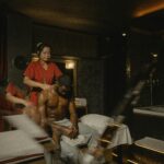 An African American man receives a relaxing massage from a masseuse in a serene spa environment.